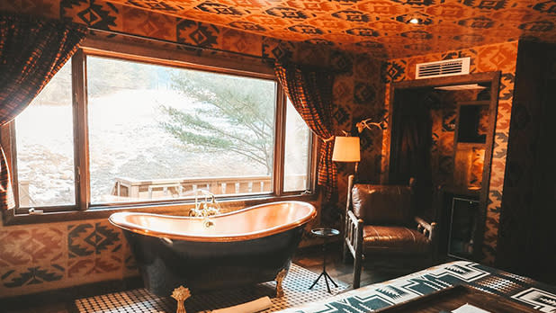 An elegant clawfoot tub tucked against a window with a wintry scene of the Catskills at Urban Cowboy