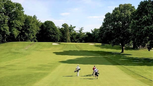 Three men walk on the course at the Oak Hill Country Club site of the 2023 PGA Championship