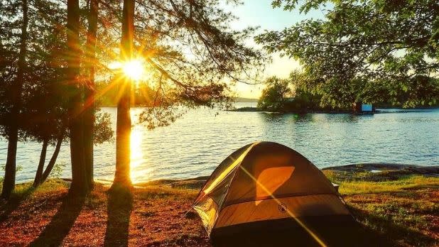 A yellow tent sitting along Lake Ontario as the sun sets