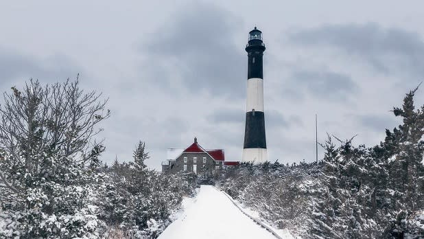 A snow-covered pathway leading to the Fire Island Lighthouse in the winter