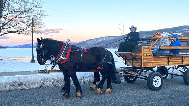 a couple riding on a horse-drawn carriage through the winter wonderlands of lake george