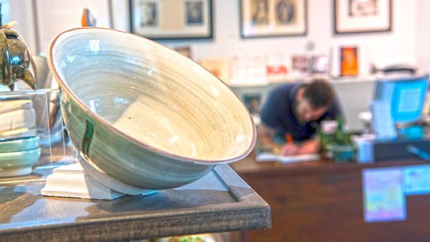 A cream and sage ceramic bowl on display in the Woodstock Byrdcliffe Guild Shop