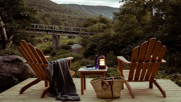 Two chairs stand on a deck overlooking sweeping views of the Catskill mountains
