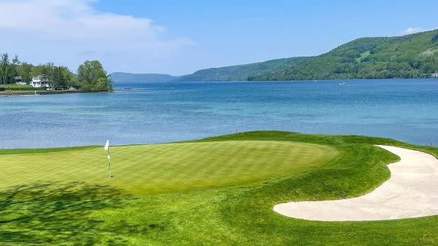 View of vibrant green golf course looking out at a view of Otsego Lake at the Otesaga