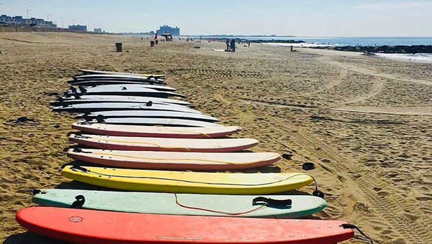 Row of surfboards lying side by side on the beach.