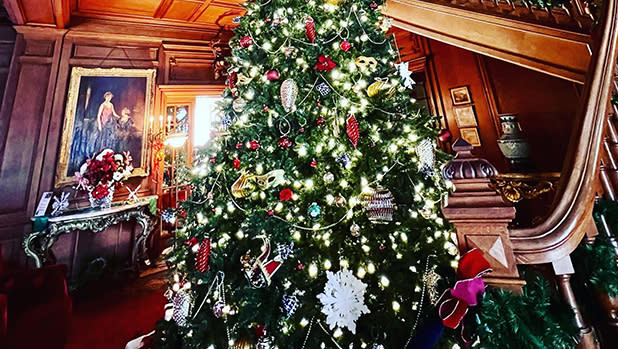A holiday tree stands in a hall by the stairs inside the Staatsburgh mansion for the Gilded Age Christmas event