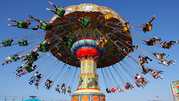 A colorful swing carousel carnival ride spinning riders through the clear blue sky in suspended seats at the Great New York State Fair.