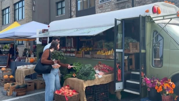 Two people browse local produce from a storefront at Lockport Locktoberfest