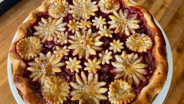 An berry pie covered in pie crust shaped like an array of flowers