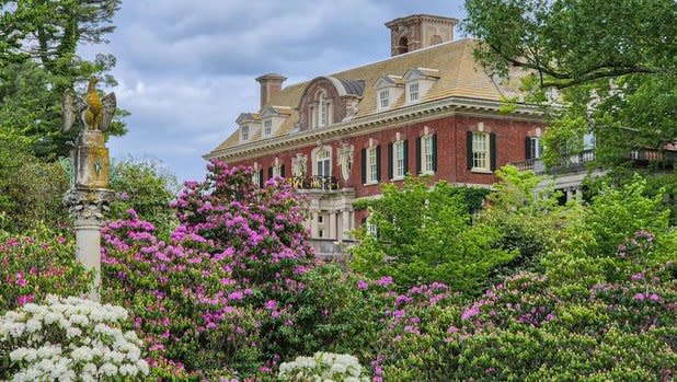 Brick Exterior of the Old Westbury House surrounded by bright green plants and pink and white flowers
