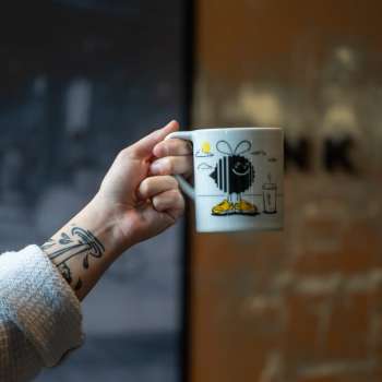 Woman's hand extended holding a mug of coffee from Bada Bean Bada Booze