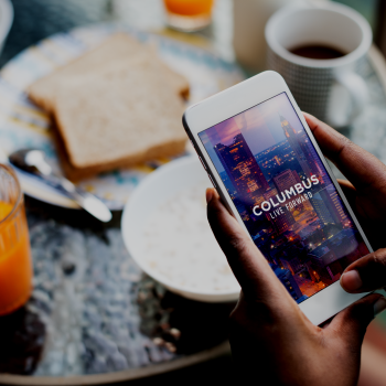 The Columbus Experience App shows on a mobile phone at the breakfast table