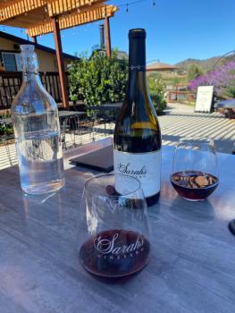 Wine bottle and glasses on a table with blue sky in the background at Sarah's Vineyard