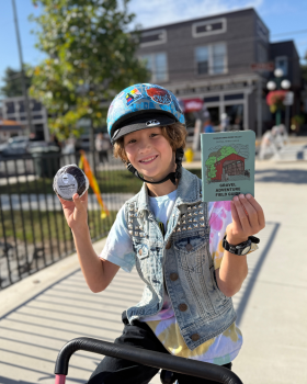 Boy in a blue helmet sits on a bike with a big smile while holding the Susquehanna River Valley Gravel Guide