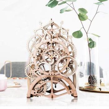 A mechanical clock kit made of laser cut wood is displayed on a table.