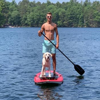 man on paddleboard with dog