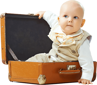 Photo of a young toddler wearing a beige suit sitting up in a suitcase.