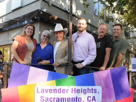A photo of six people smiling with a rainbow sign with the words Lavender Heights, Sacramento, CA