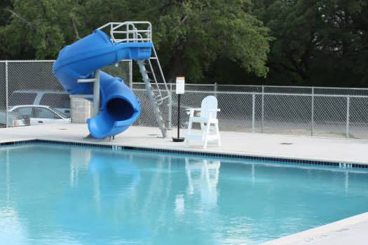 Outdoor pool with a slide and lifeguard chair.