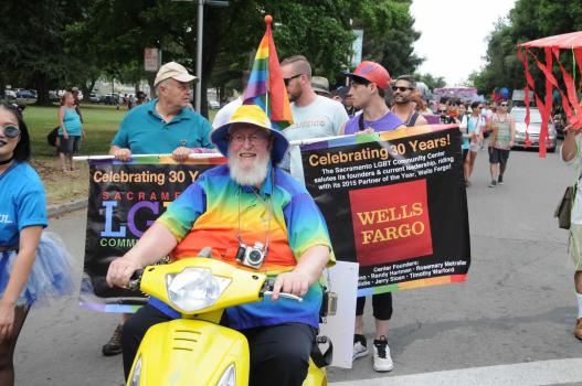 A photo of a bearded man riding a yellow scooter and wearing a rainbow shirt, followed by Pride Parade marchers holding a sign celebrating the LGBT Center's 30th Anniversary