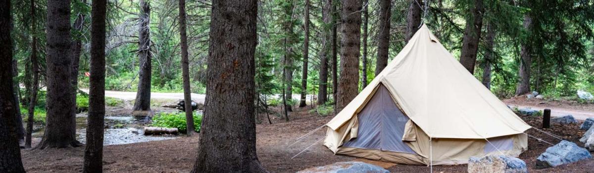 A white bell tent in a forested area of the Utah Valley, USA.