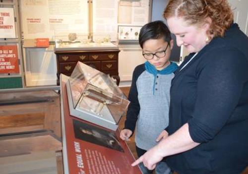 White woman and Ssian boy look at a museum display at Museum of Historic Annapolis