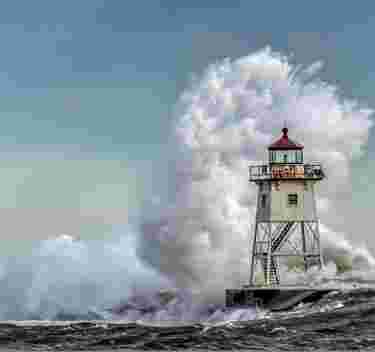Storm Season - wave breaking over lighthouse - by David Johnson