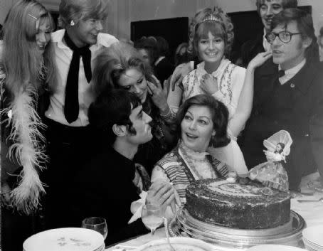 Ava Gardner sits in front of a large birthday cake surrounded by cast of The Ballad of Tam Lin including Ian McShane and Roddy McDowall.