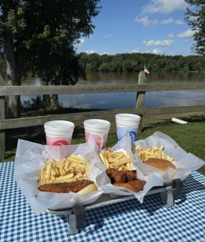 Picture of yummy food and refreshing beverages on a table at The Fence Restaurant with flowing river in background