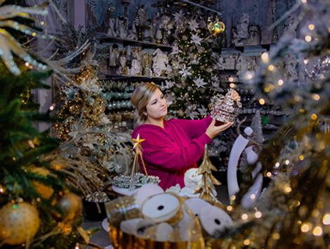 A woman holds up a gingerbread house while surrounded by holiday décor in DeWayne's Christmas Land in Selma, NC.