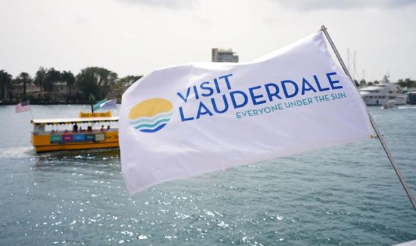 Visit Lauderdale Flag blowing in the wind with the Water Taxi riding behind it.
