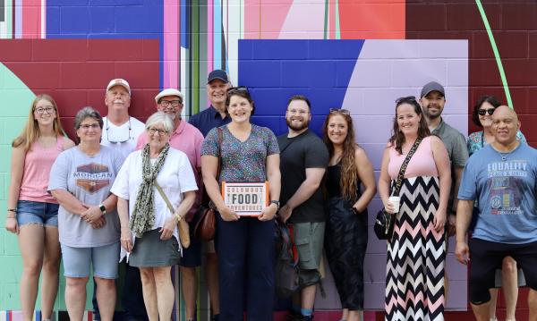 A tour group standing in front of a mural.