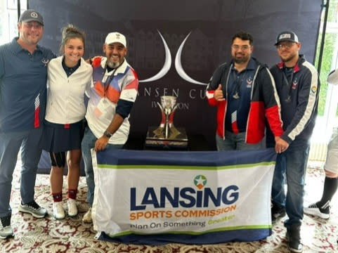 Footgolf players smiling with a Lansing Sports Commission flag and the Jansen Cup.