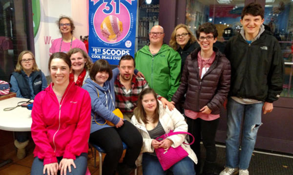 A group of teens and young adults out to dinner. The group is smiling for the photo.