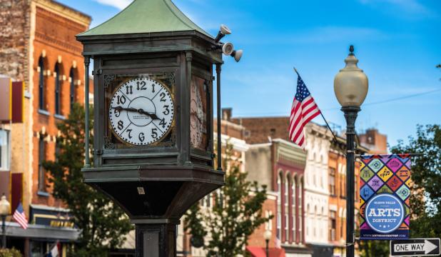 A clocktower in front of a view of downtown Glens Falls