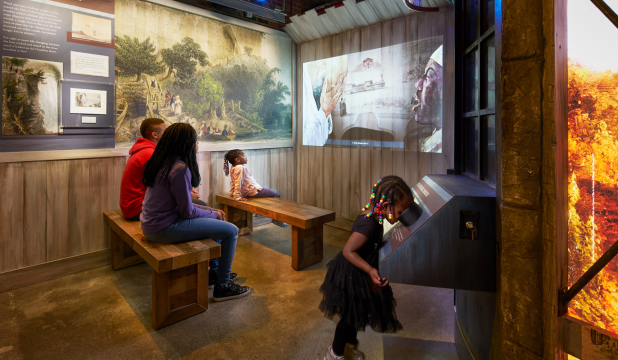 A group watches an educational movie in a room at the Niagara Falls Underground Railroad Heritage Center
