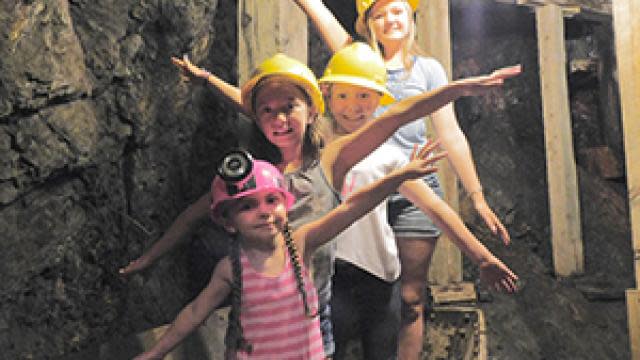 Kids posing in mine cart in tunnel on tour