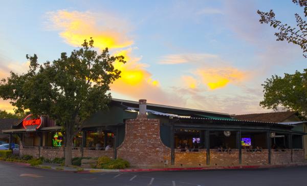 Brick restaurant patio with people seated outside while sun sets in the background