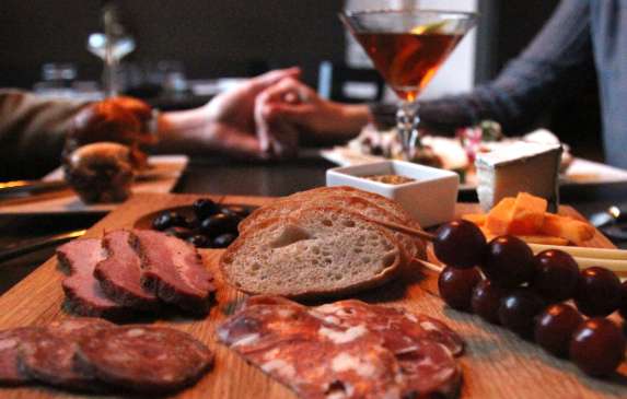 A couple holding hands at a table with a charcuterie board and martini