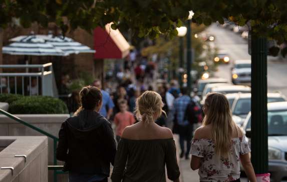 Three women walking down Kirkwood Avenue on a fall evening