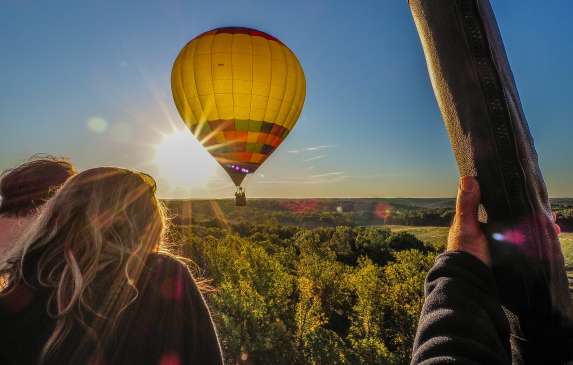 A hot air balloon with passengers lingers behind another hot air balloon
