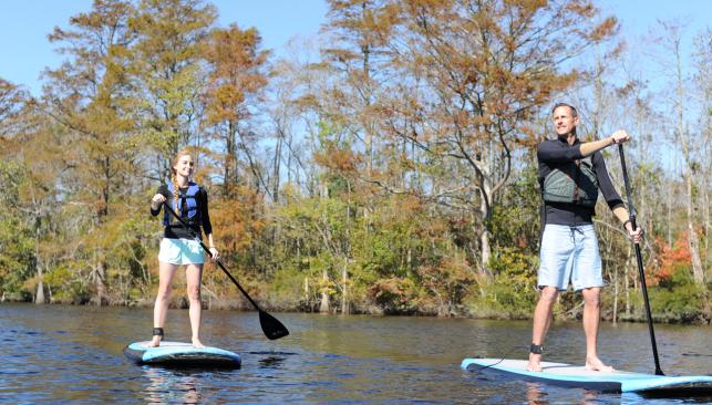 Two people with life jackets stand up paddle boarding in Chesapeake