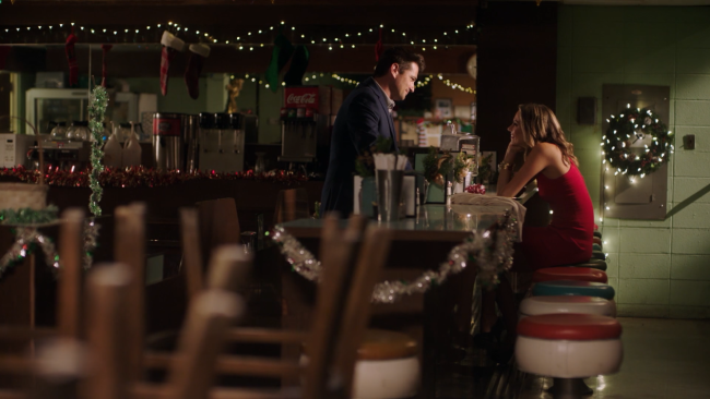 A man and a woman at a counter in a diner.