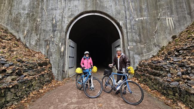 Cyclists are shown in front of the Big Savage Tunnel on the Great Allegheny Passage.