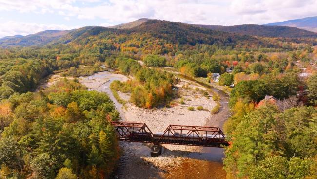 Granite State Scenic Railway - Train Crossing Bridge with Mountains in Background