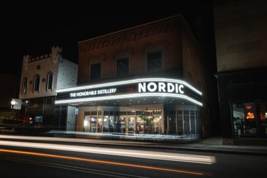 The exterior of the Honorable Distillery with its restored Nordic marquee it up in the dark