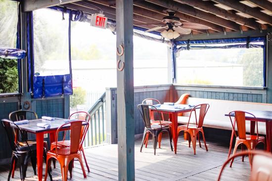 An outdoor porch seating area of a restaurant with red seats and black tables