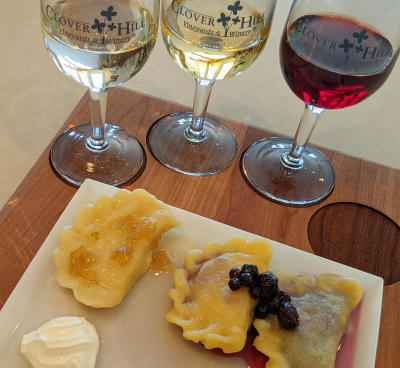 Pierogi on a plate with sour cream and red and white wine glasses in the background