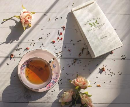 cup of tea alongside bag of tea and flowers