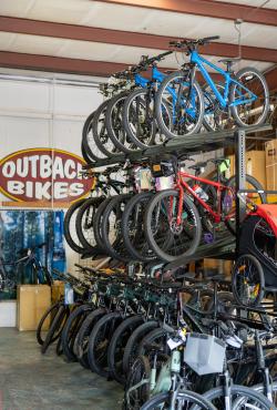 Three-tiered rack of bikes with Outback Bikes logo in the background.